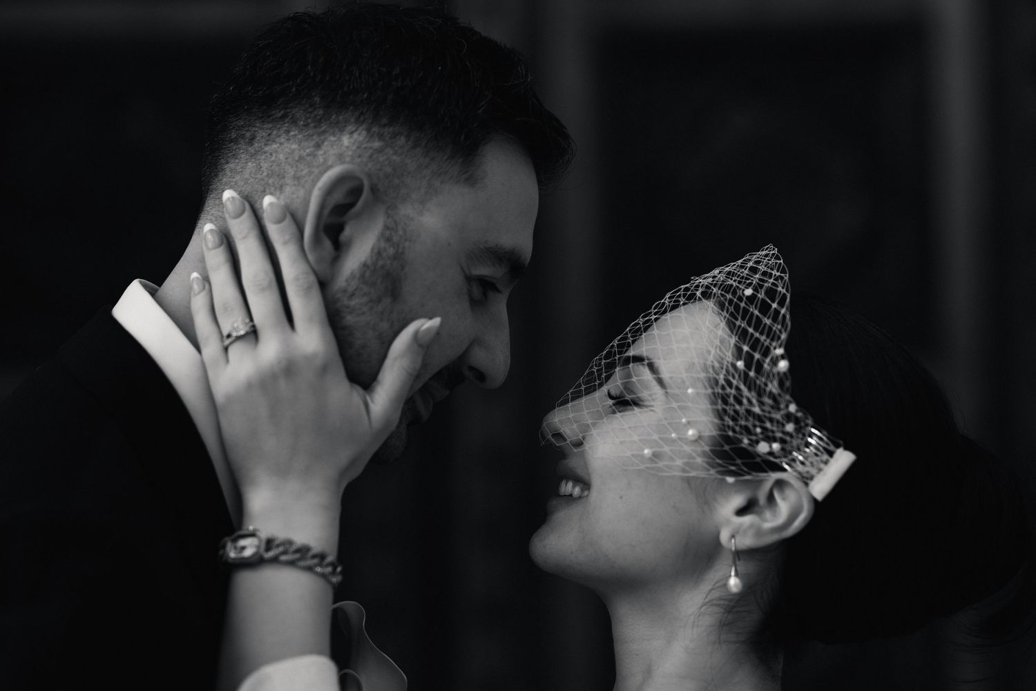 Black and white close-up of a newlywed couple laughing together on their wedding day.