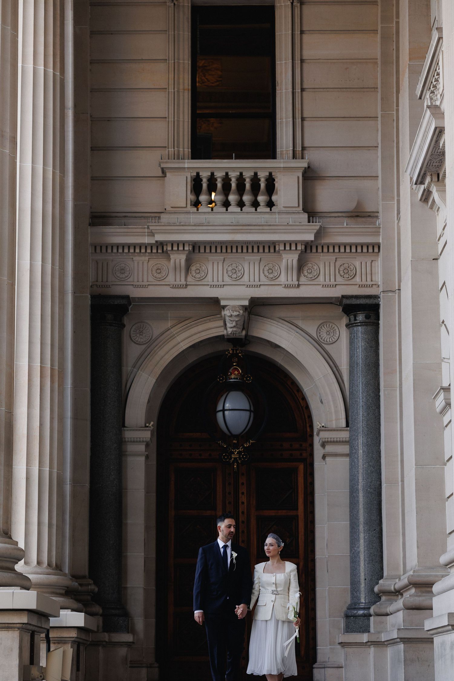 Bride and groom framed by the architecture of a Melbourne building on their wedding day.