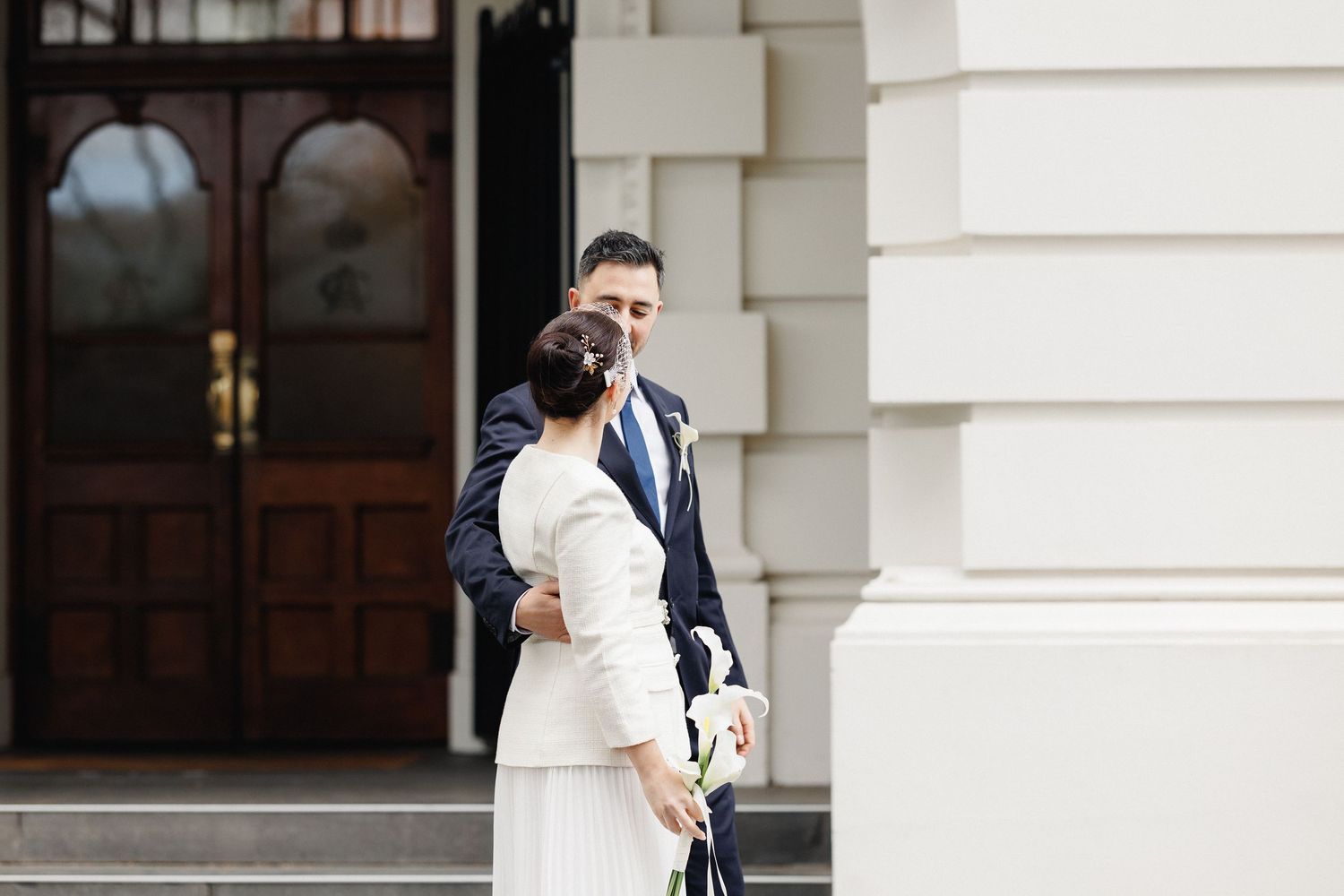 Bride and groom embracing outside a Melbourne building after their wedding ceremony.