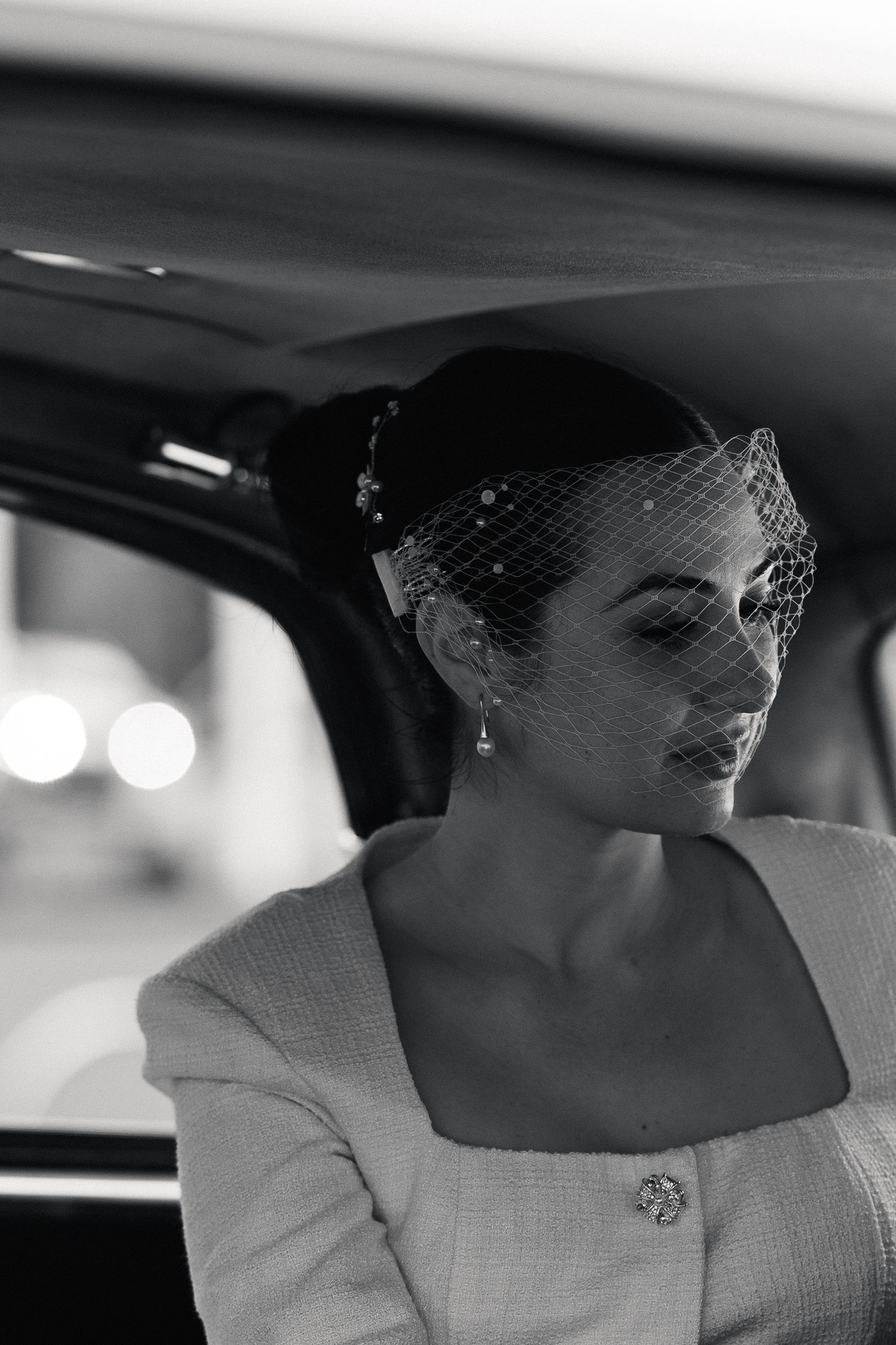Candid black and white portrait of a bride smiling inside her wedding car.