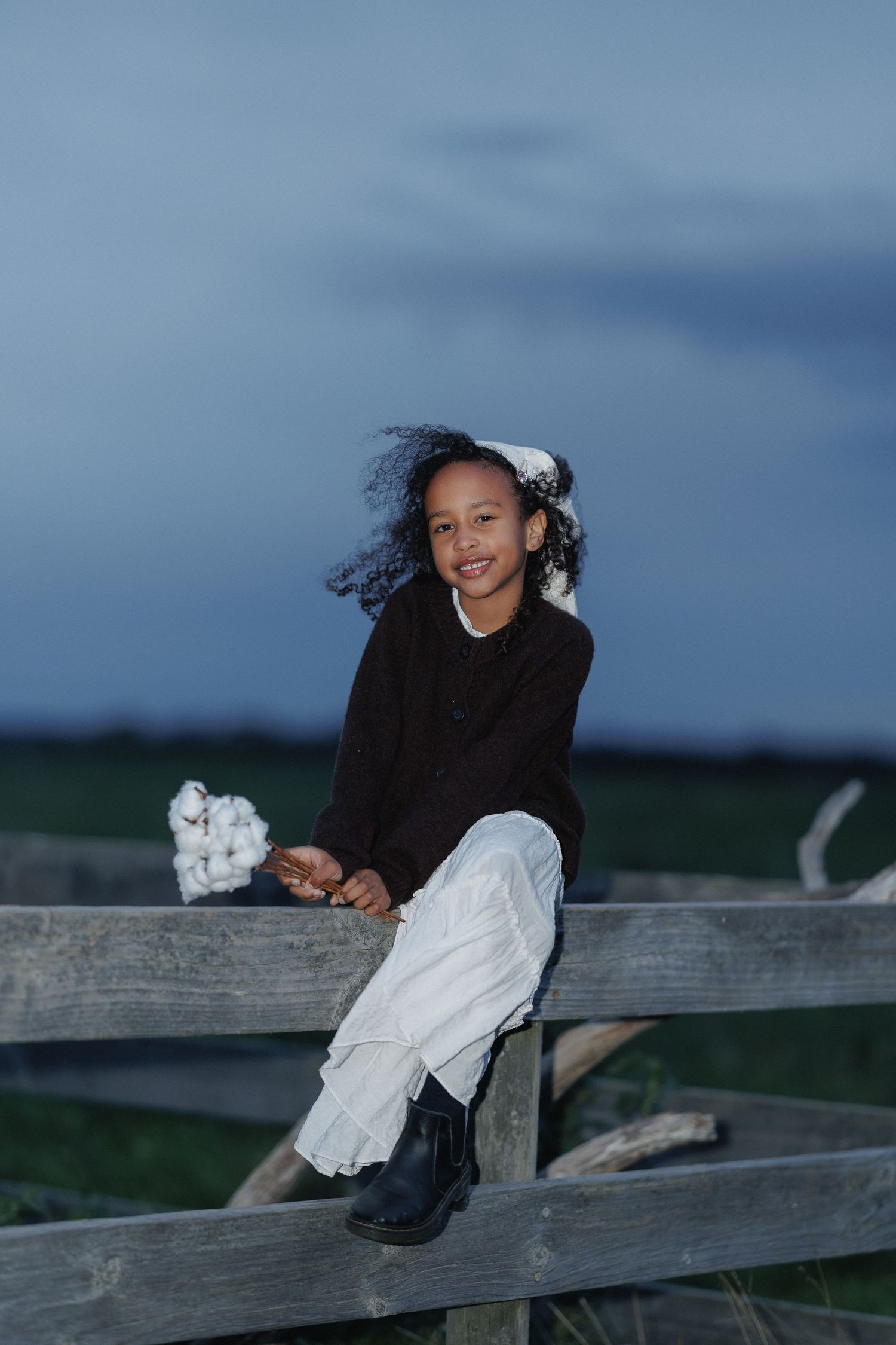 Child sitting outdoors at dusk during a relaxed family photography session