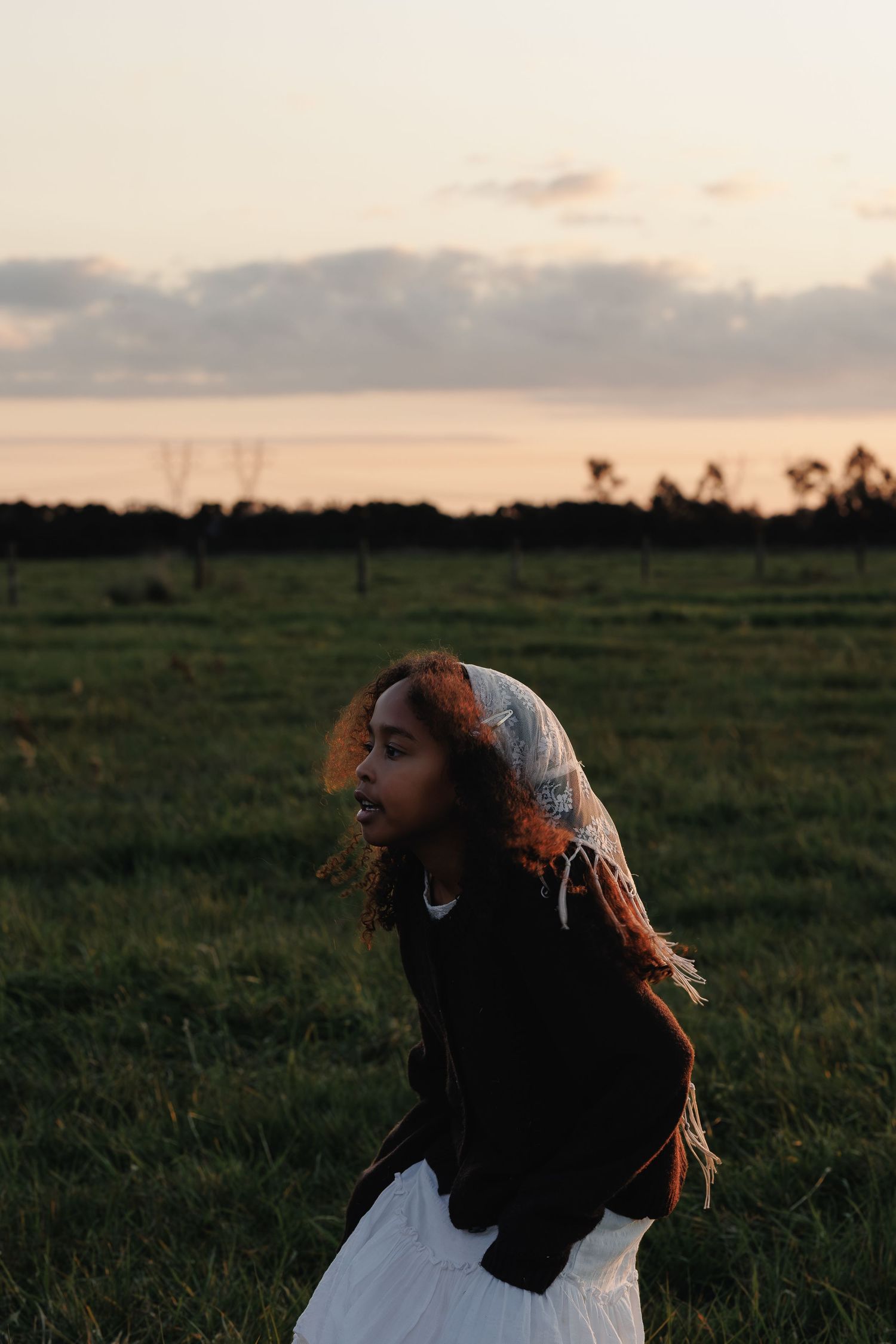 Child laughing in an open field at sunset during a relaxed family photo session.