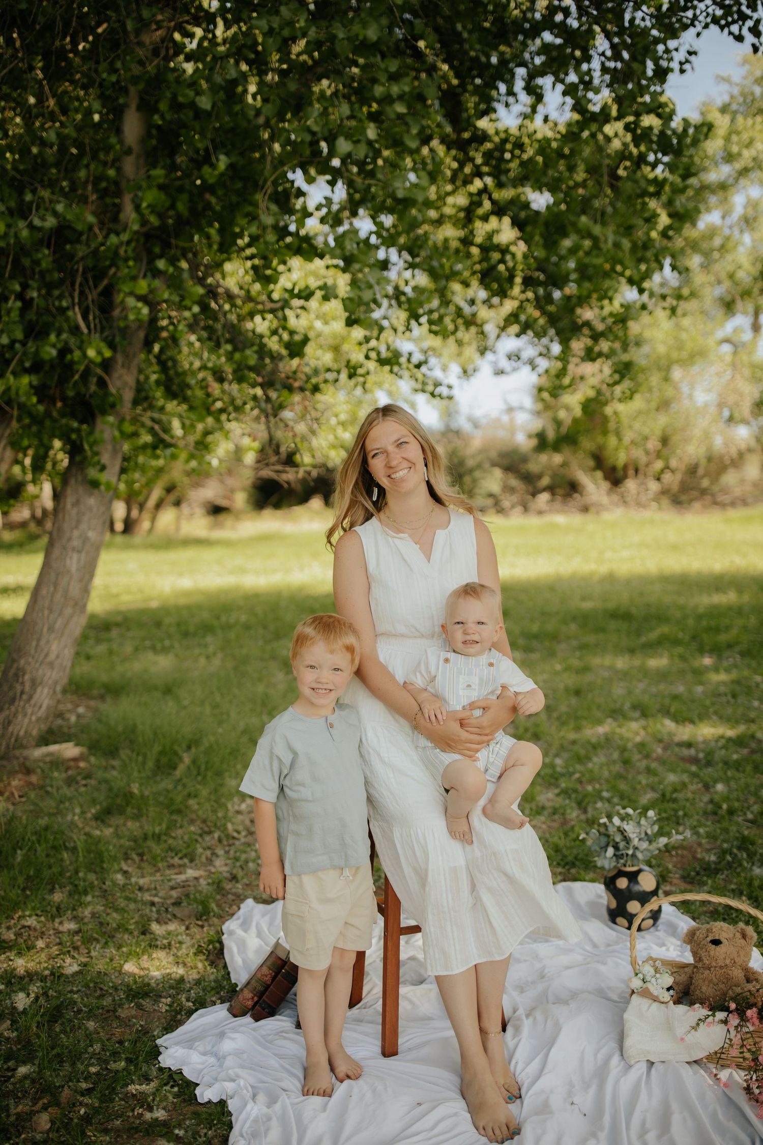 A mother is holding her two children as they all smile at the camera together.