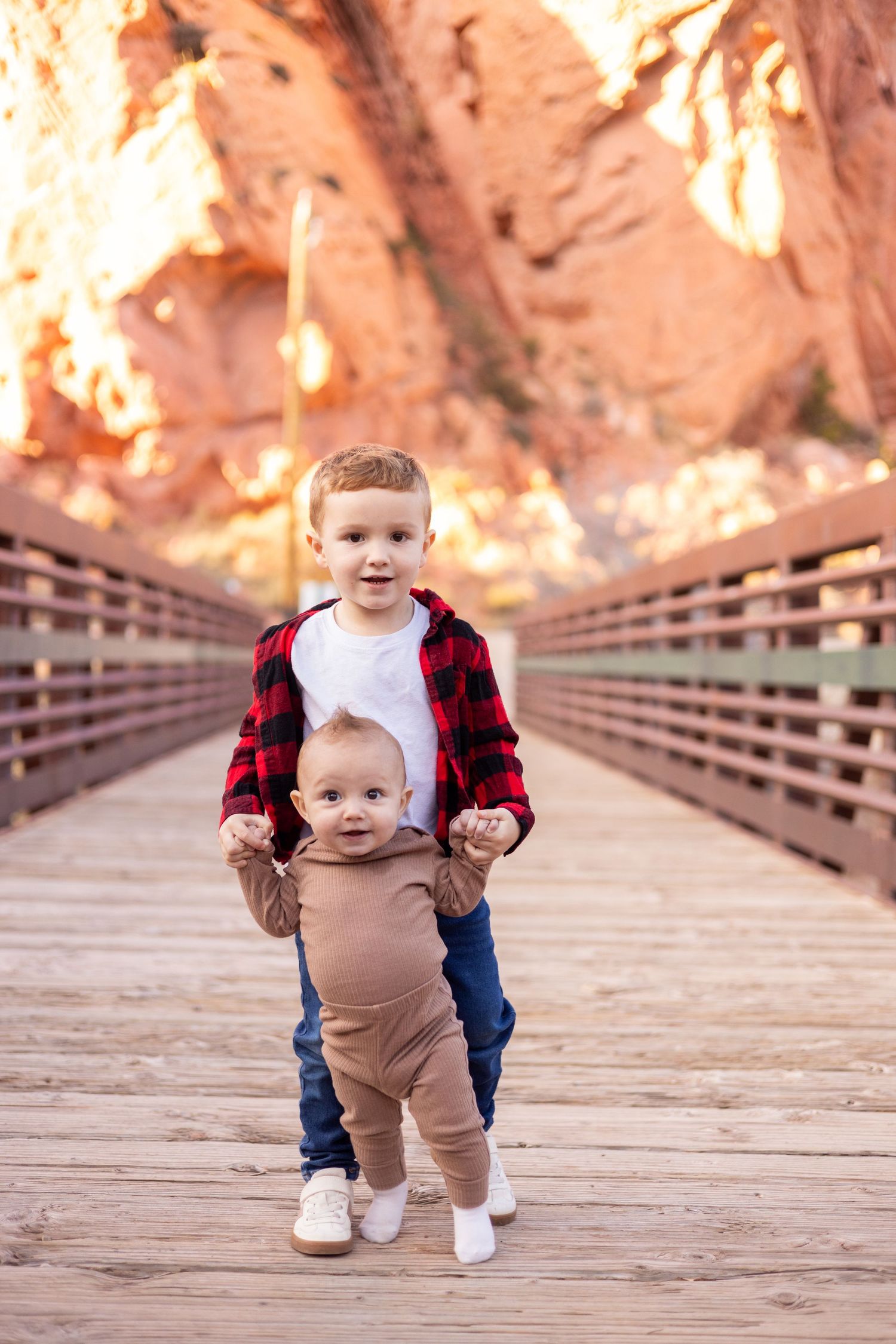 Two siblings giggling and holding hands during a photography session in Cedar City, Utah.