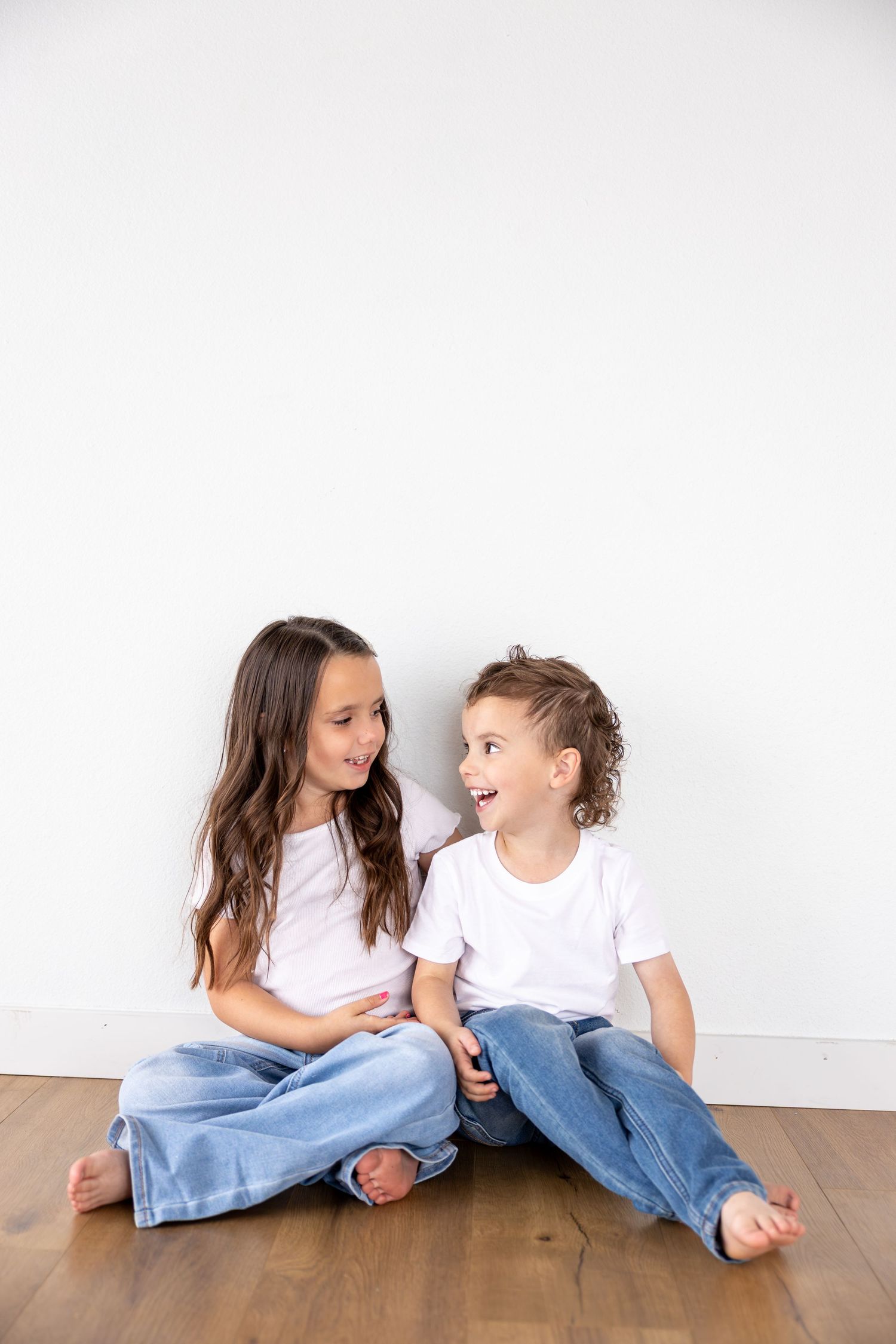 A brother and sister are looking at each other and giggling.