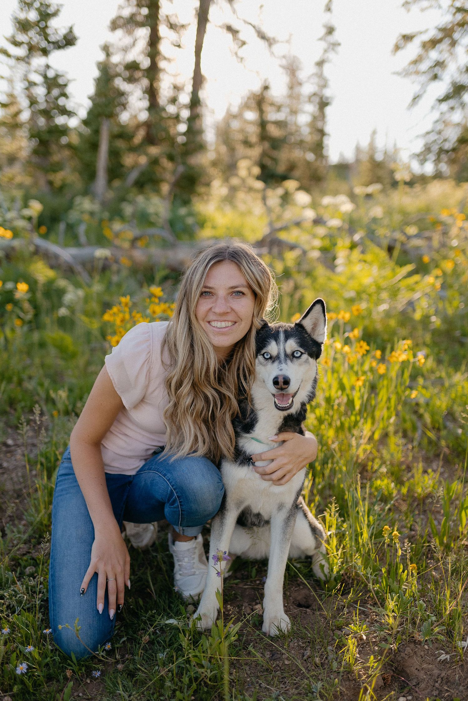 A girl and her dog are sitting in a glowy flower field together.