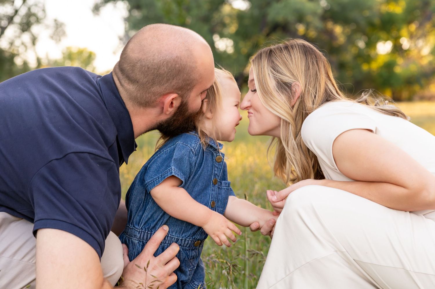 A toddler giving her momma a kiss while the dad smiles at both of them.