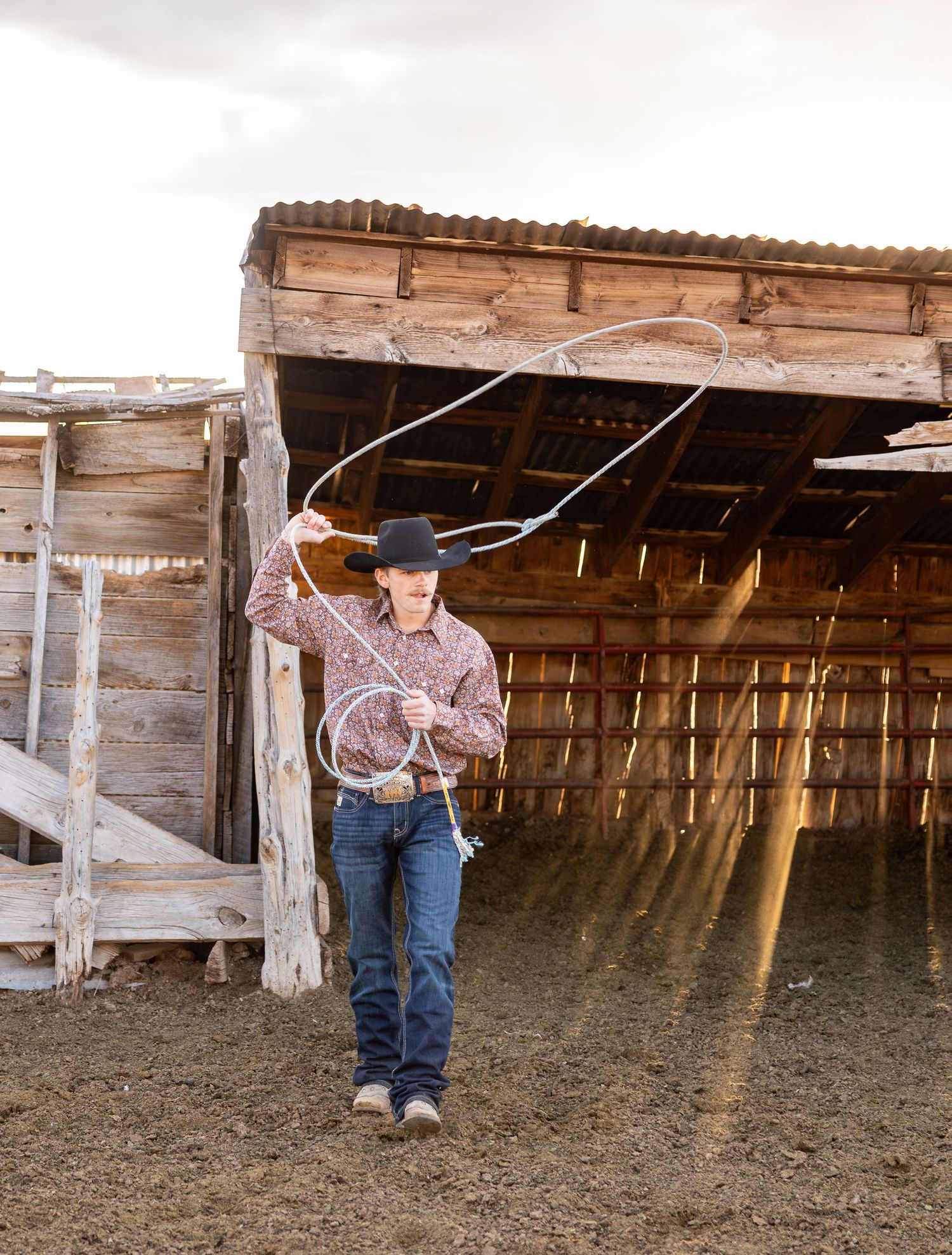 A senior boy is trying to rope a calf on his family ranch during his Senior Photoshoot in Cedar City, Utah.