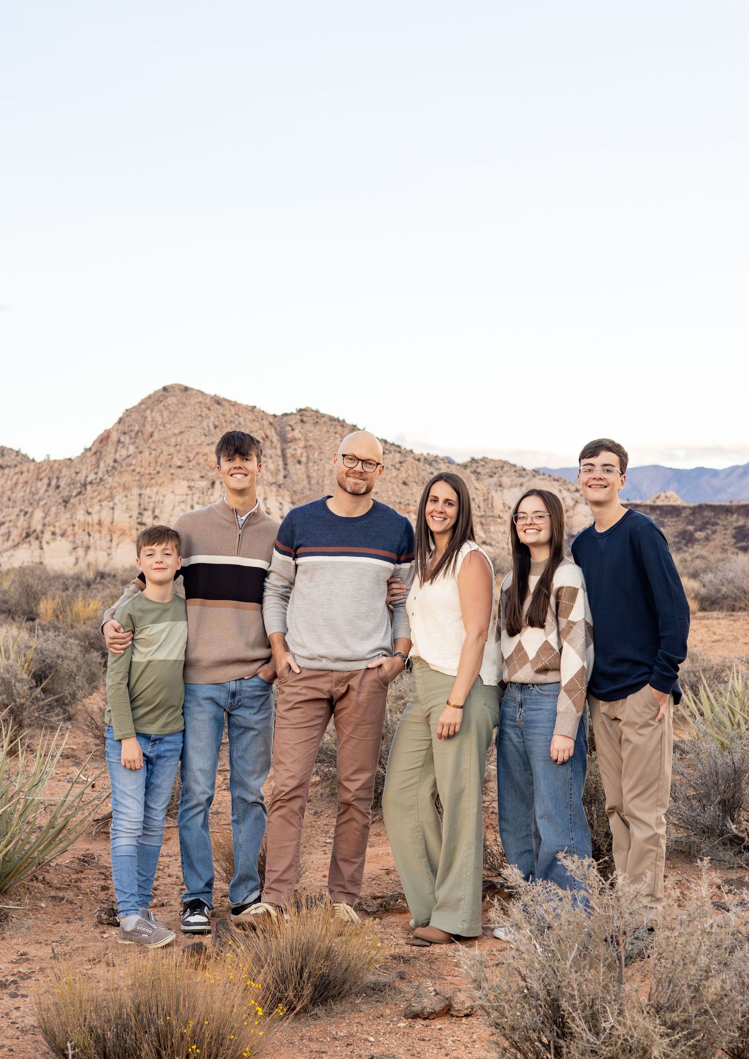 A family of 6 smiling at the camera during their Family Photos in Snow Canyon State Park.