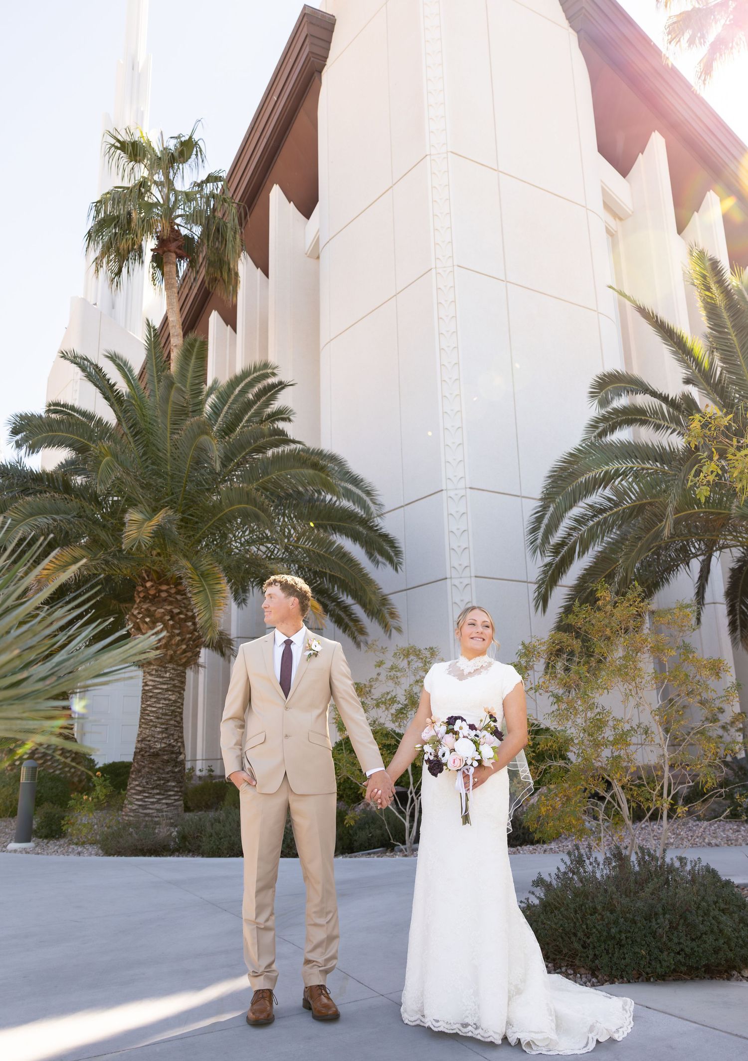 A bride and groom are holding hands in front of the Las Vegas LDS temple.