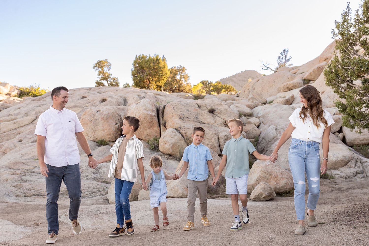A family holding hands, laughing, and walking together during a family photoshoot at Three Peaks.