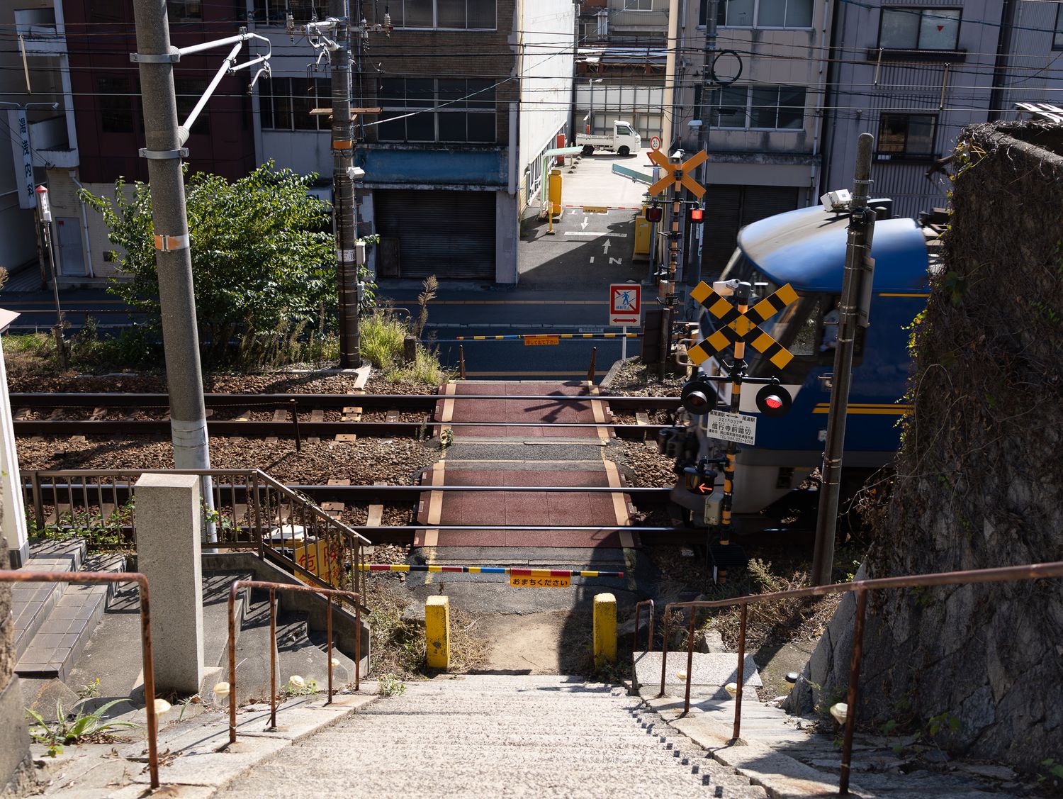 Train tracks and platform at a Japanese railway station with buildings visible in the background.