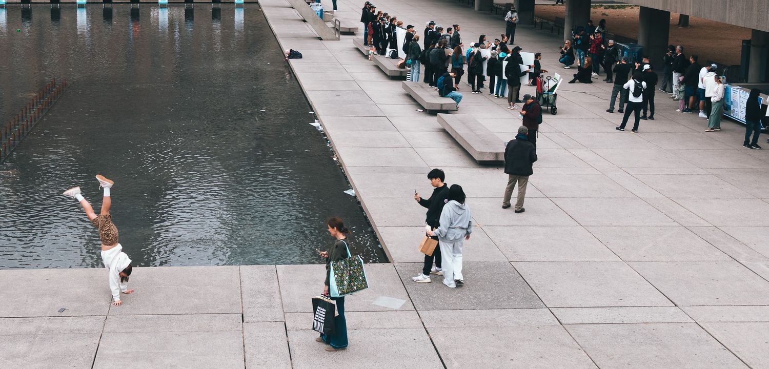 People walking along waterfront promenade on cloudy day.