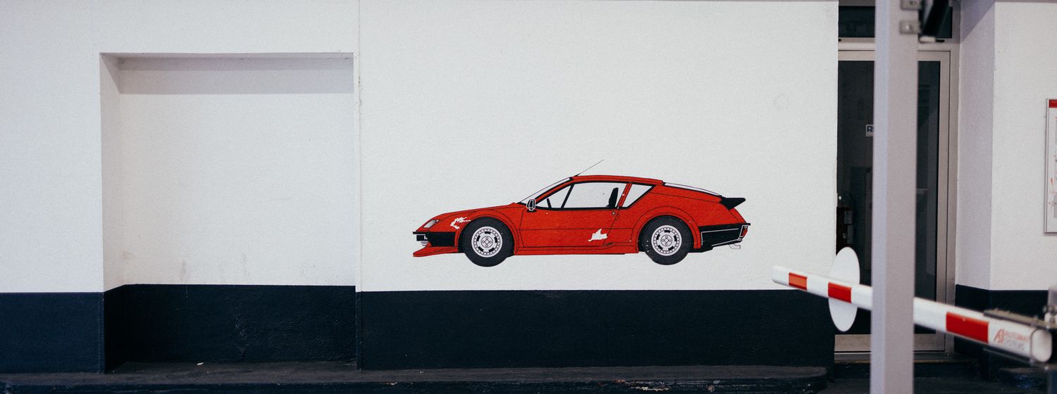 Minimalist white wall with small red vintage car illustration.