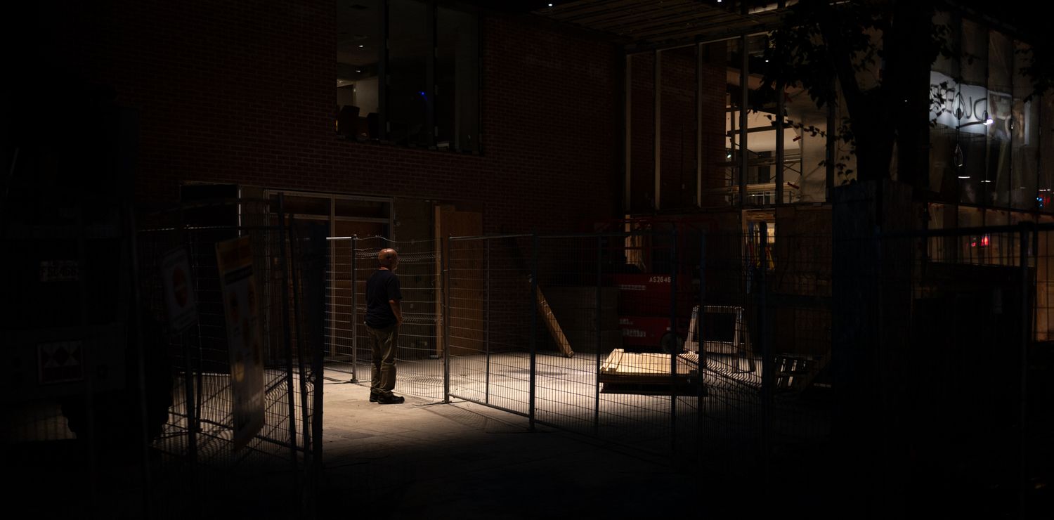 Dark atmospheric interior of an abandoned building with empty chairs and furniture casting eerie shadows.