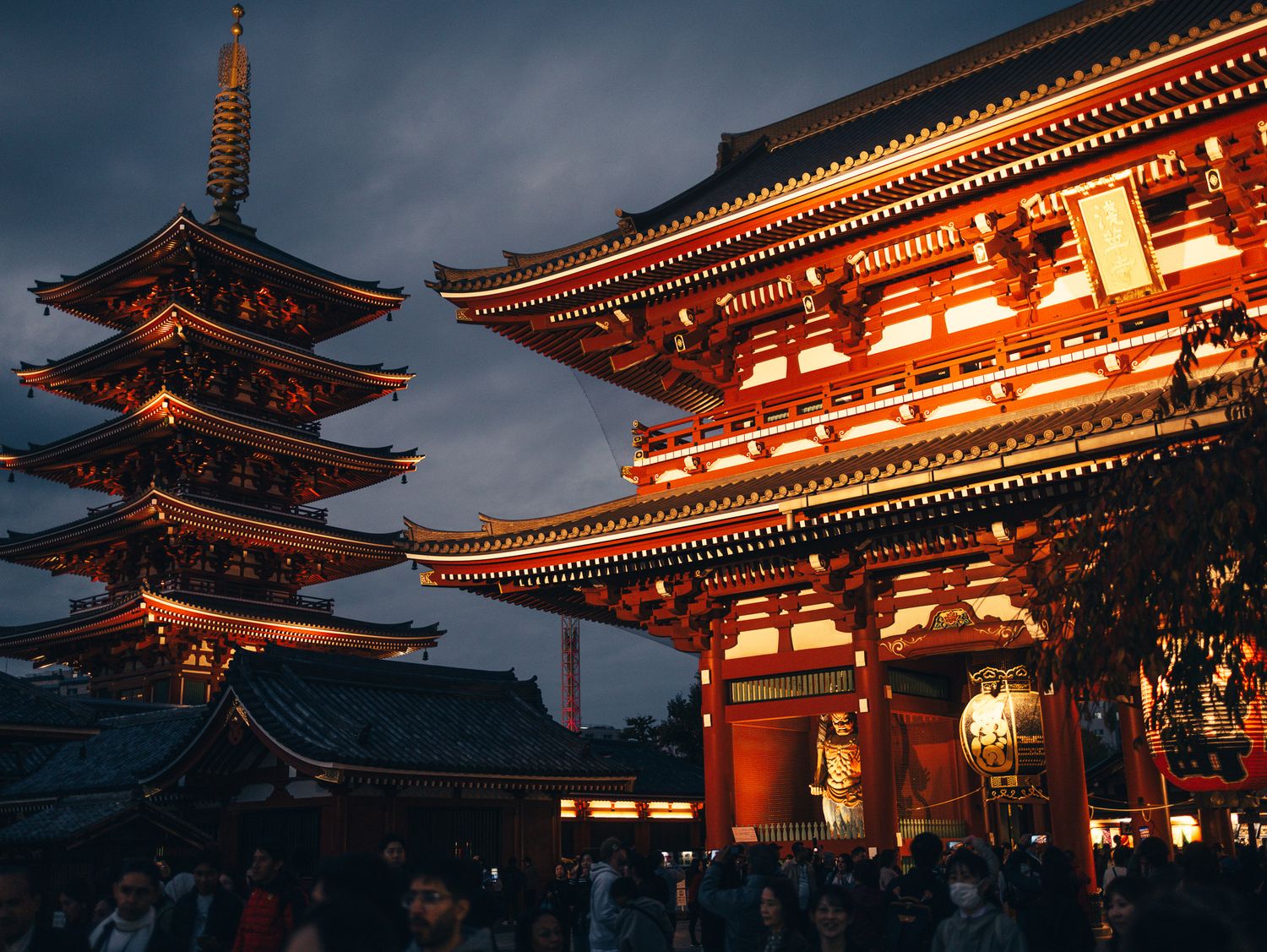 Traditional Japanese temple pagodas illuminated with orange lights at twilight.