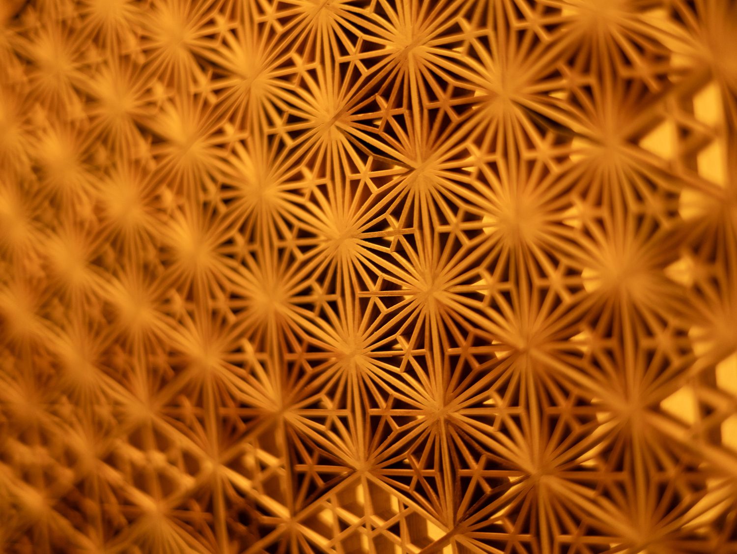 Abstract pattern of golden geometric star shapes creating a repeating design.