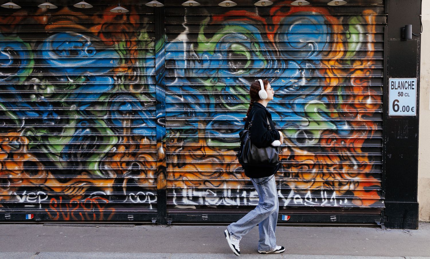 Long wall covered in vibrant graffiti artwork with orange and blue tones.