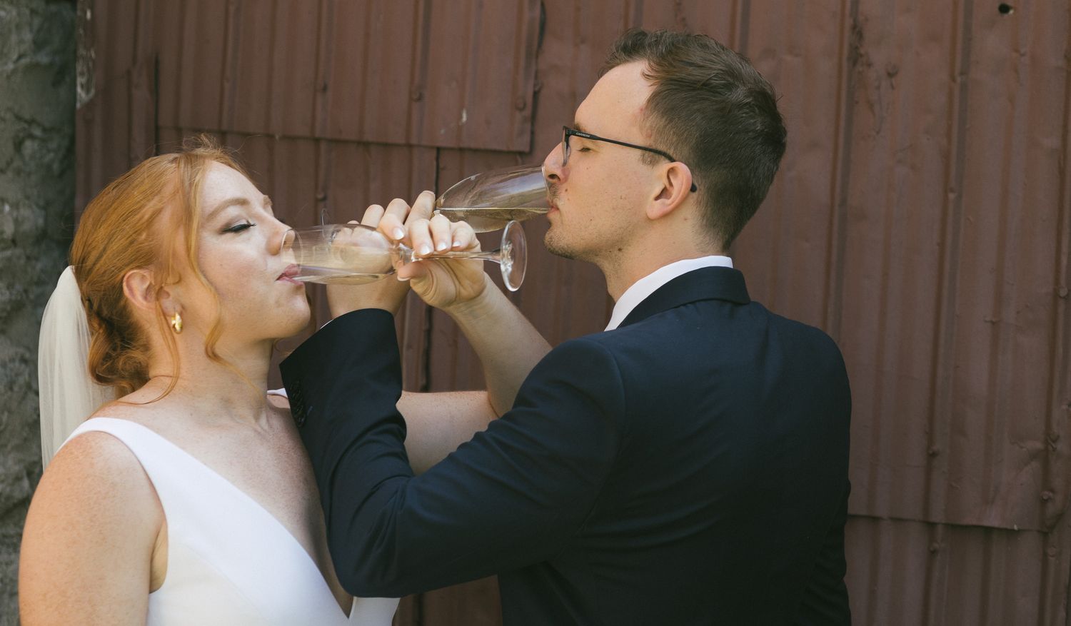 A bride and groom share a celebratory drink together during their wedding celebration.