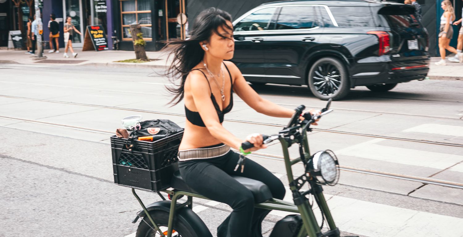 Cyclists riding along urban street on sunny day.