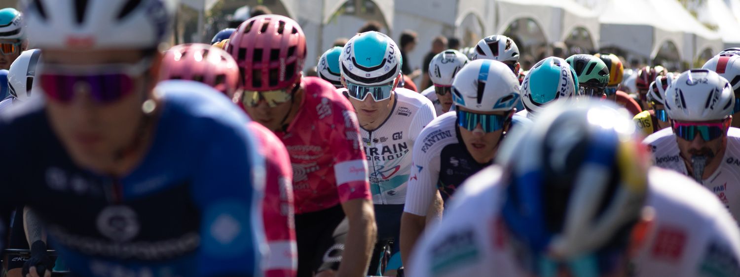 Crowded peloton of cyclists wearing colorful jerseys and helmets during a race.