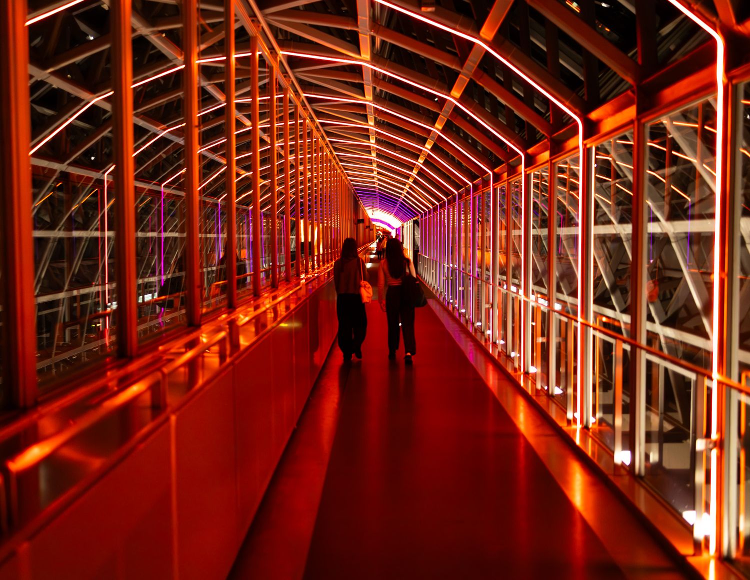 Long illuminated corridor with red lighting creating a dramatic perspective effect.