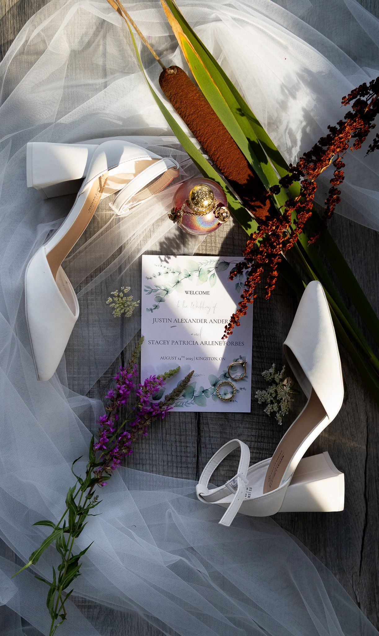 Wedding invitation and floral details with white tulle veil and purple flowers.