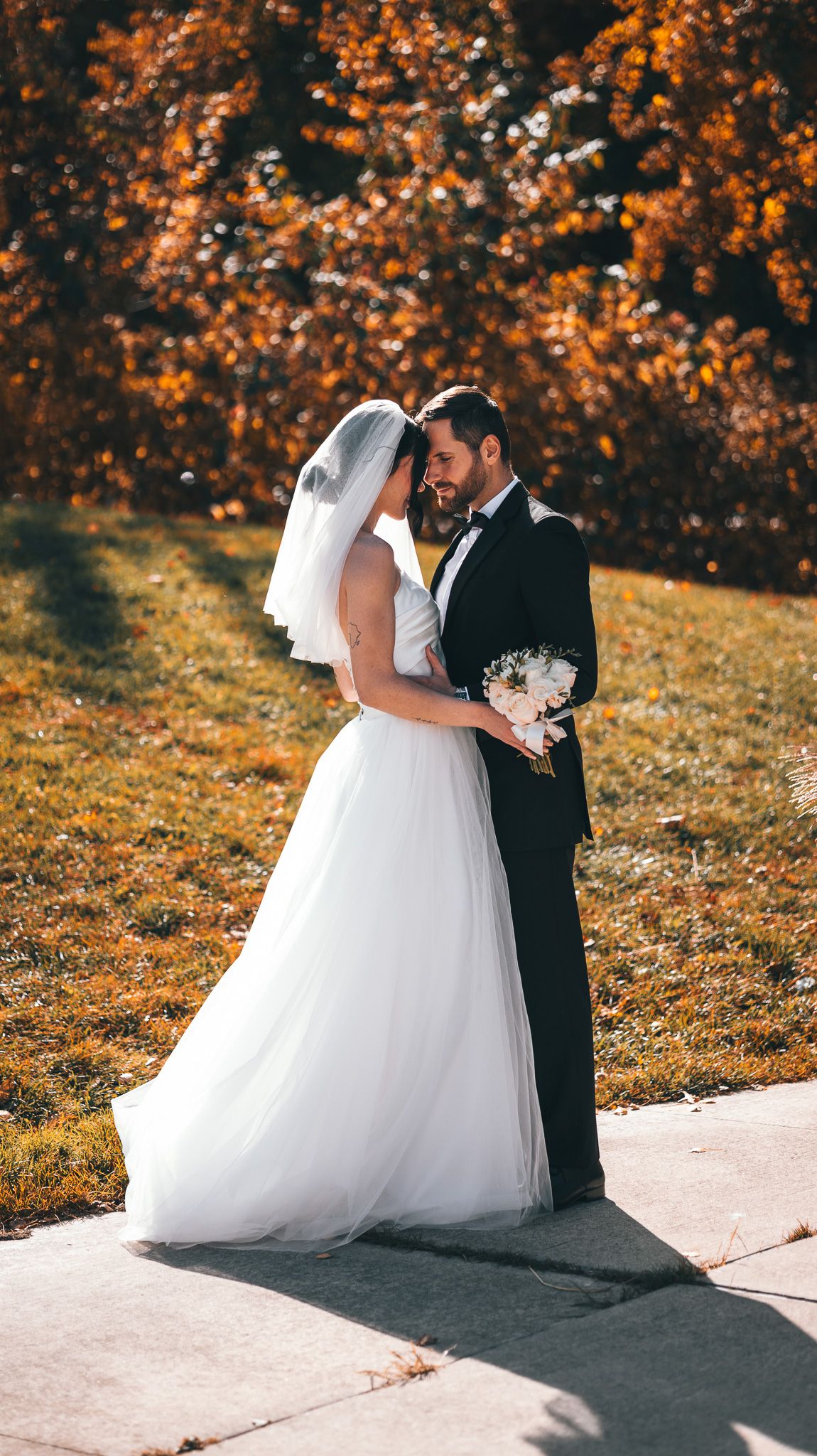 Romantic autumn wedding photoshoot with fall foliage and golden light.