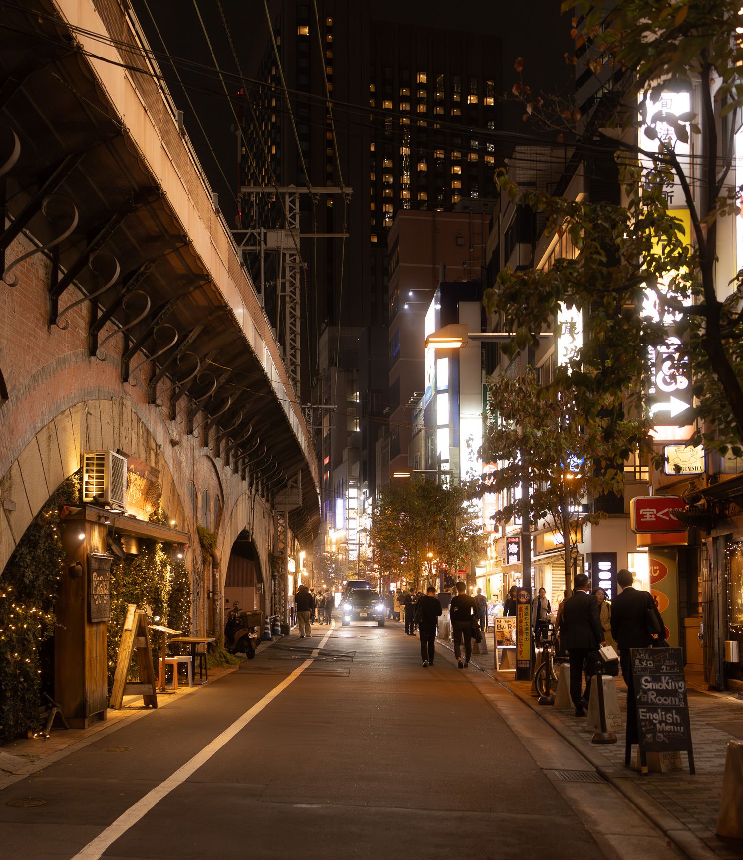 Illuminated urban shopping arcade with string lights and arched ceiling at night.