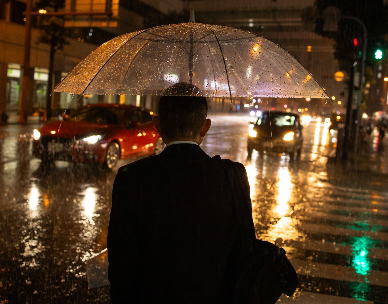 Rainy night city street with reflective puddles and glowing street lights creating an atmospheric scene.