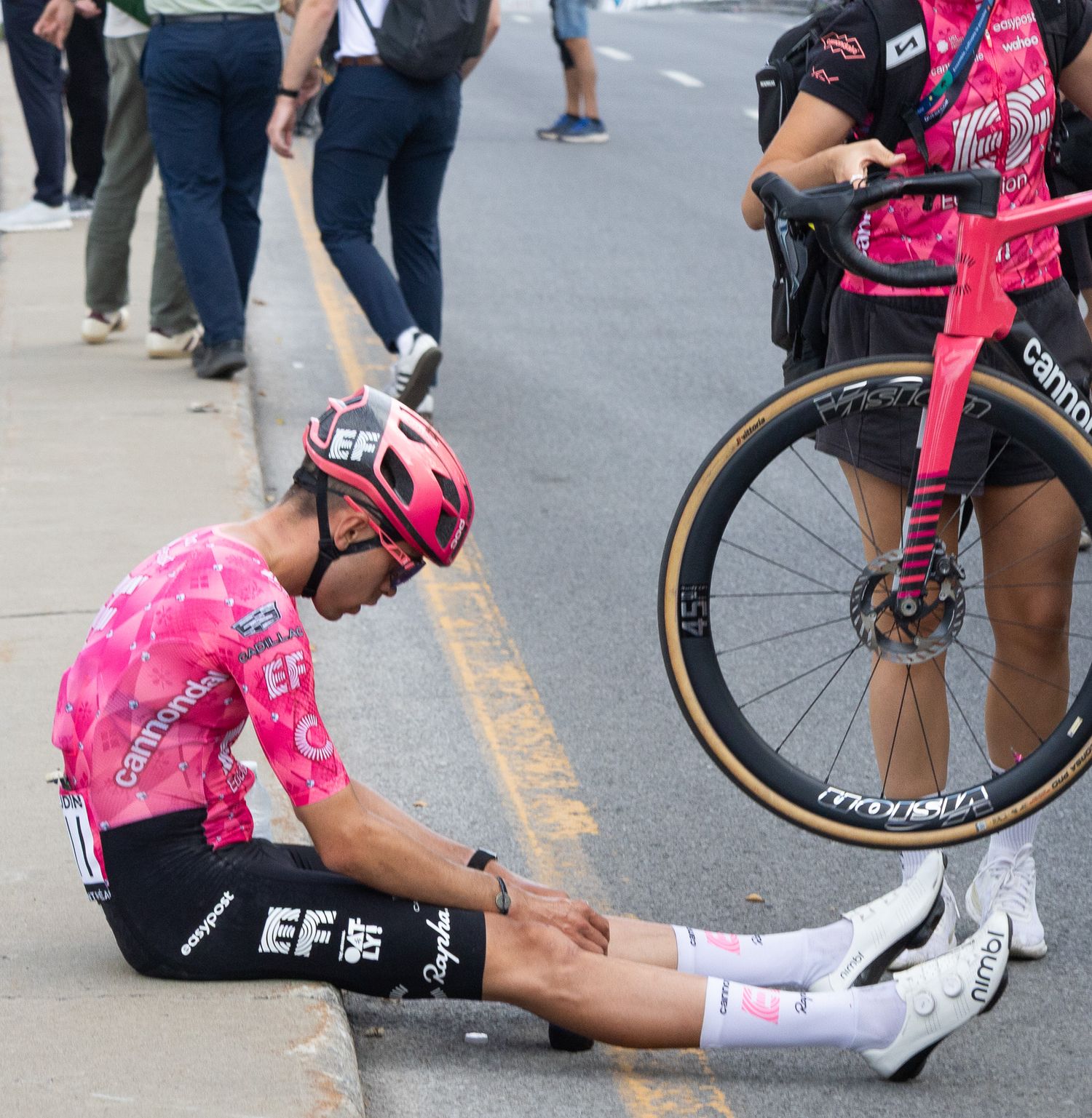 Cyclist in pink jersey adjusting equipment during a race break.