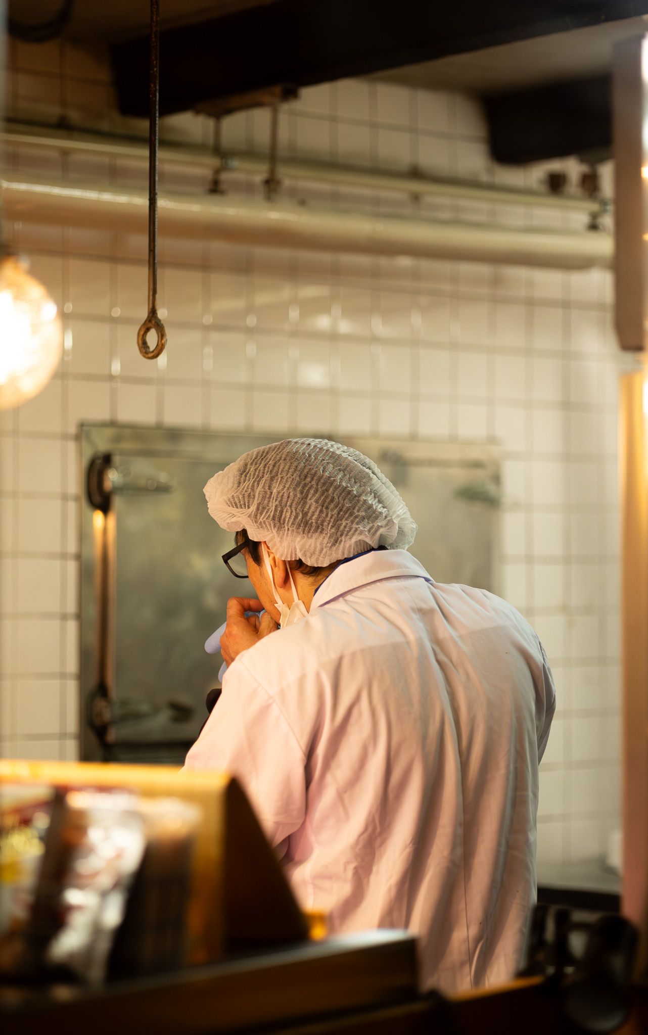 Kitchen workers in white uniforms and hairnets working in a commercial kitchen setting.
