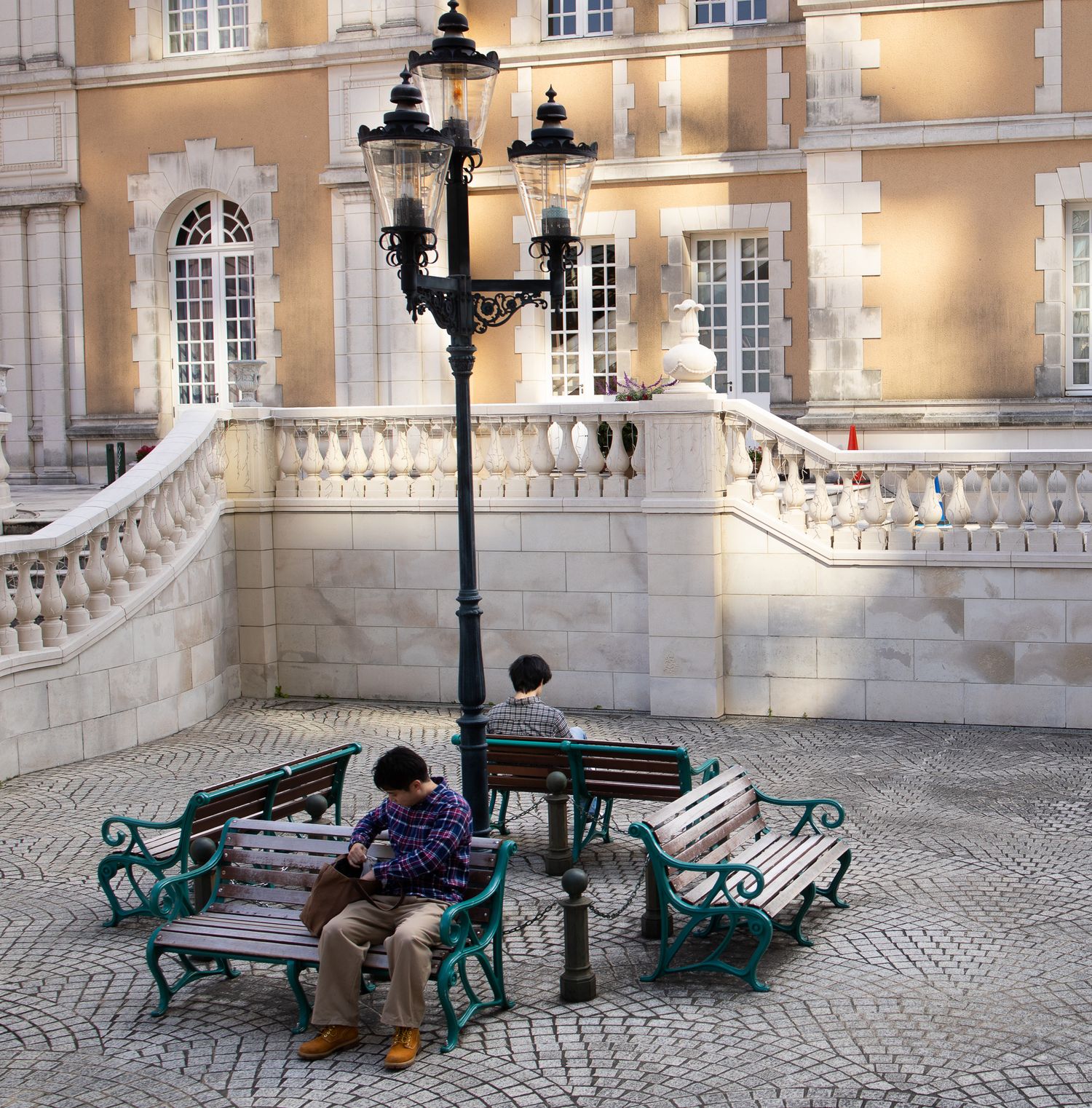 Ornate palace courtyard with green benches and stone balustrades at dusk.