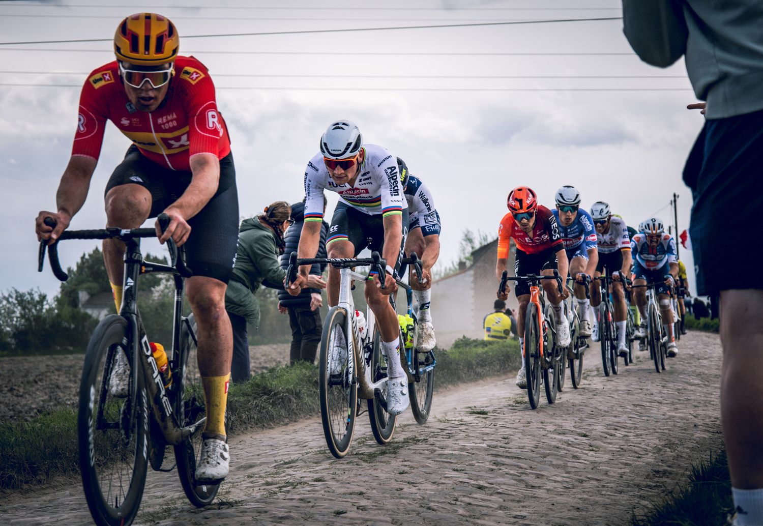 Cyclists riding mountain bikes in a line on a dusty dirt trail during an outdoor competition.