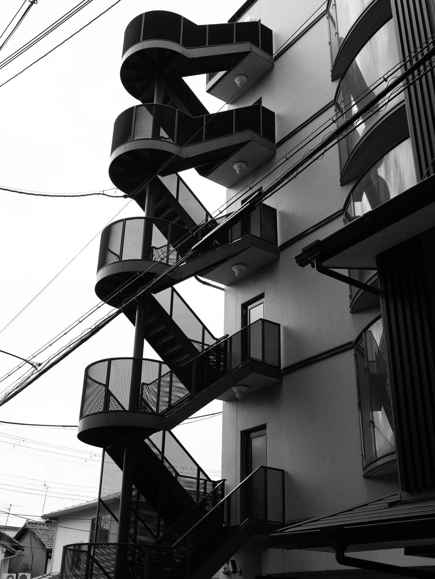 Black and white architectural detail of spiral fire escapes on building exterior.
