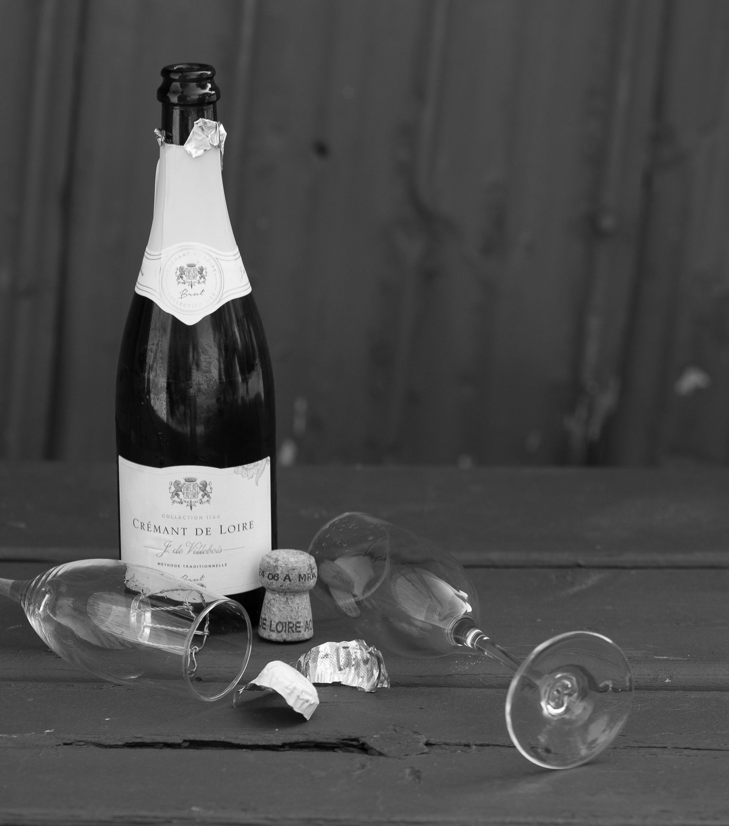 Fallen champagne bottle and glass in dramatic black and white photography.
