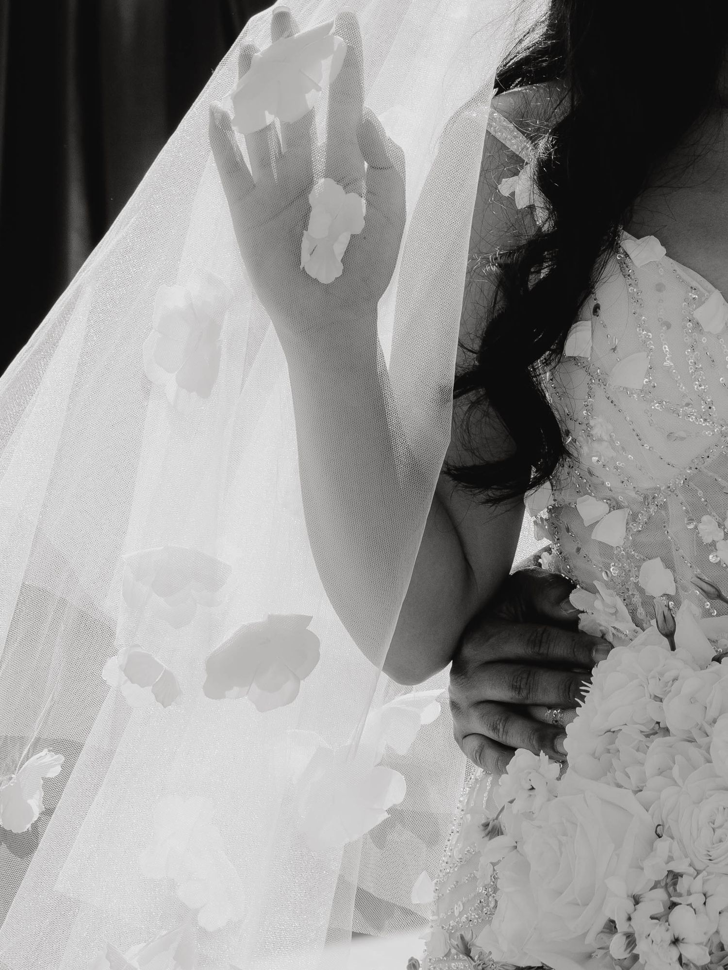A close-up detail of white wedding dress fabric with delicate lace and floral embellishments.