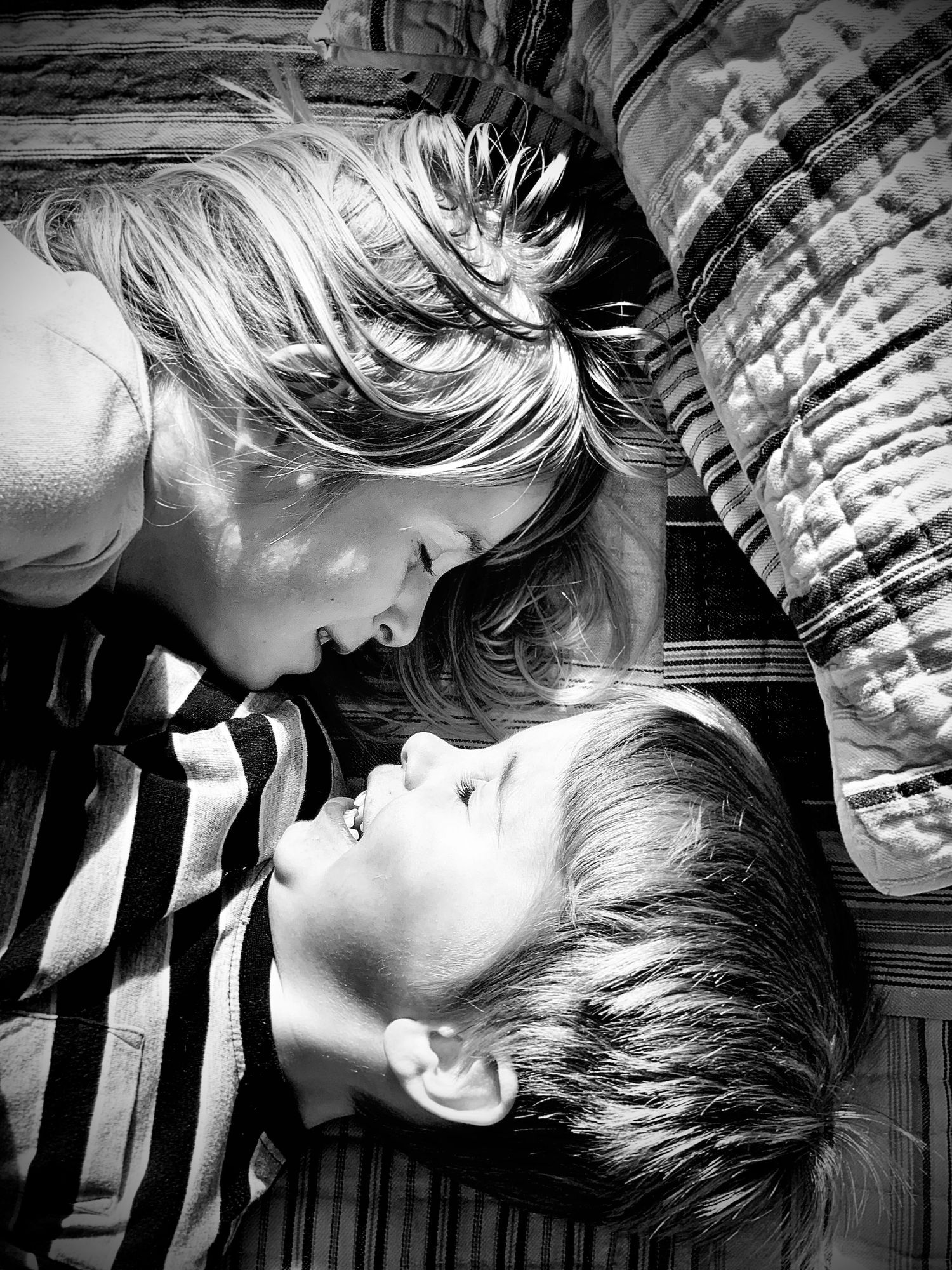 Two children lying face to face on the floor in a black and white close-up photo.