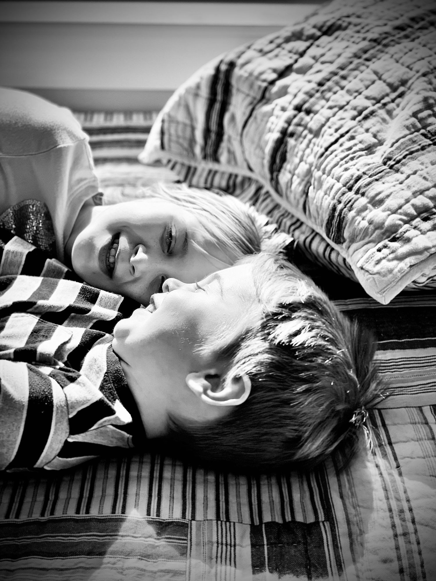 Two children lying on the floor laughing together in a black and white photo.
