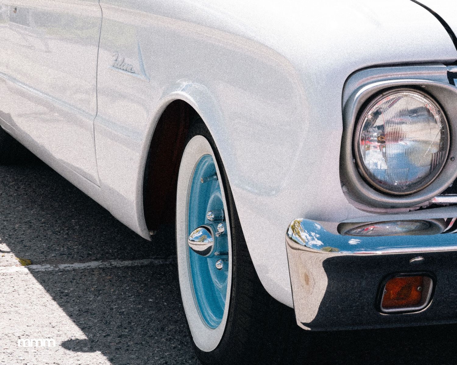 White classic car with blue-rimmed whitewall tires and chrome details.