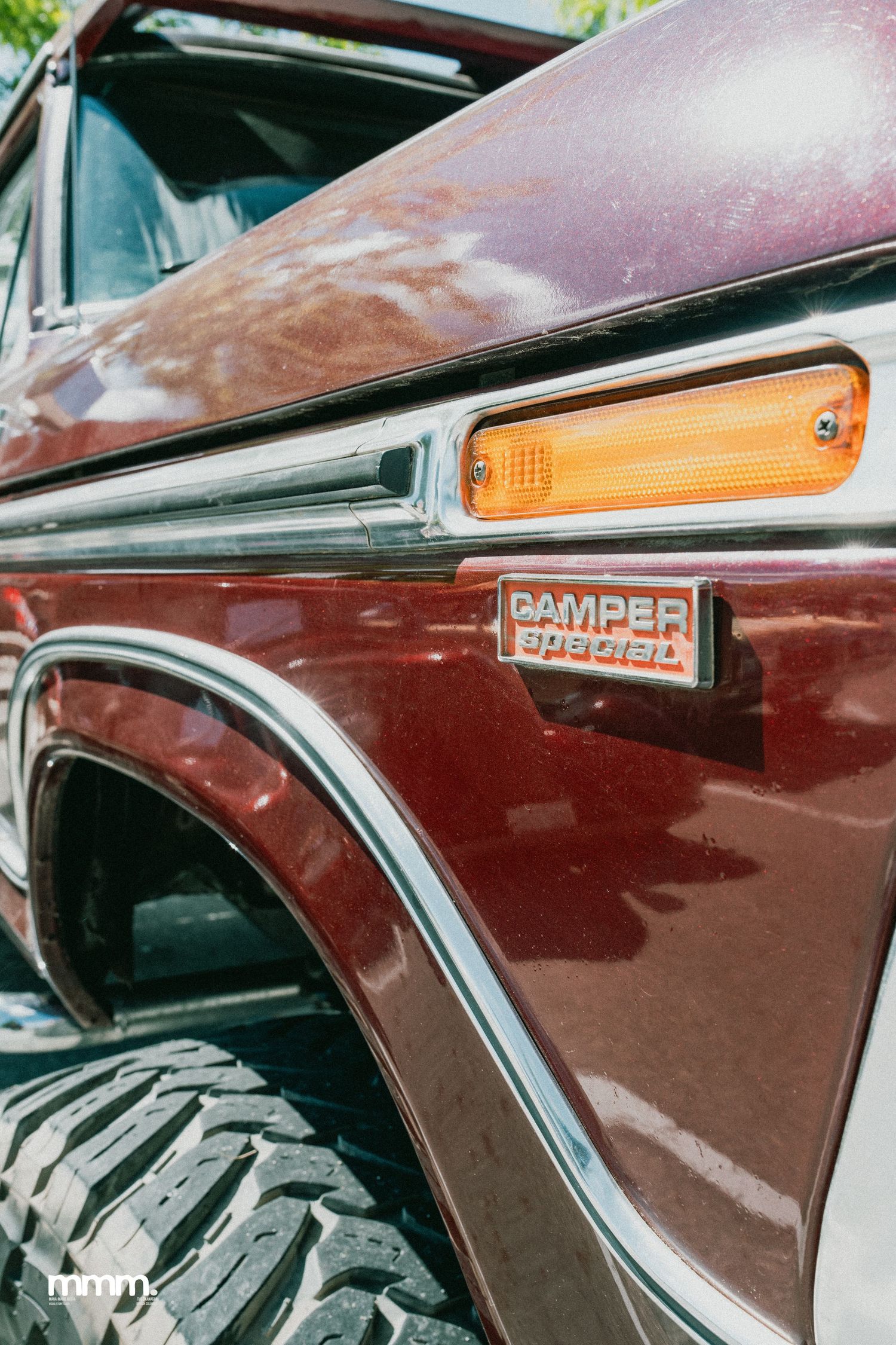 Close-up of burgundy Ford truck fender with Camper Special badge and amber turn signal.