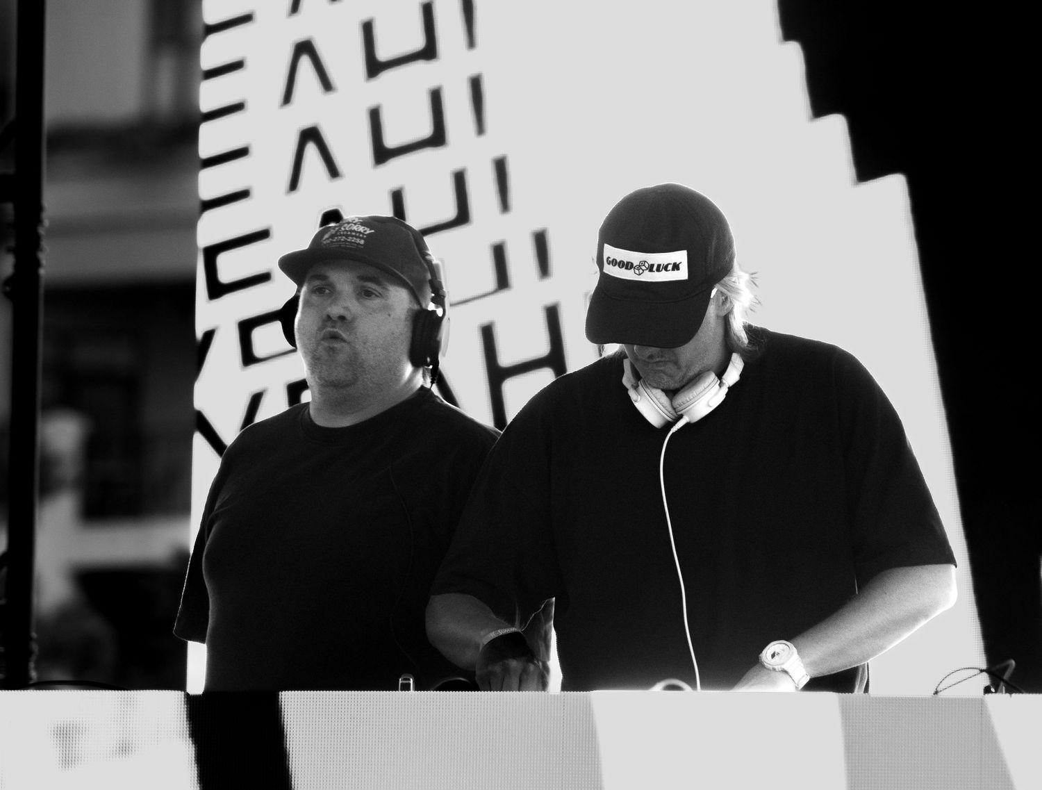 Two DJs performing at an outdoor music event in black and white photography.