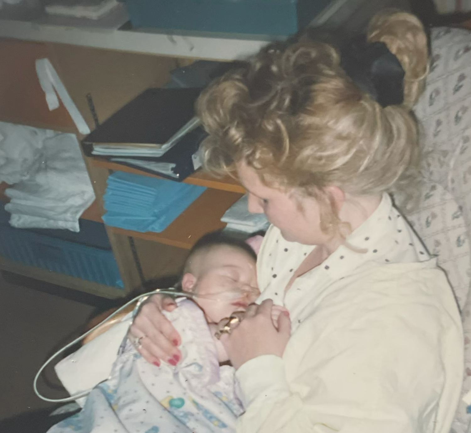 A mother tenderly holds her newborn baby in a hospital room shortly after birth.