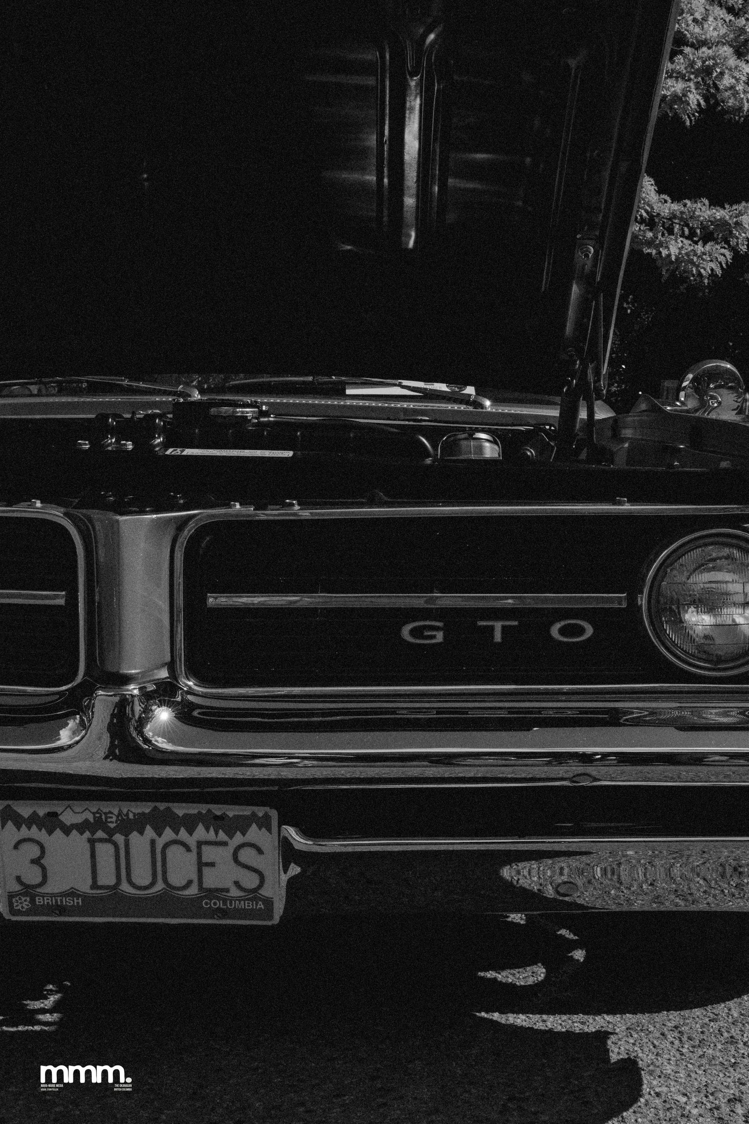 Black and white close-up of classic Pontiac GTO front grille with 3 DUCES license plate.