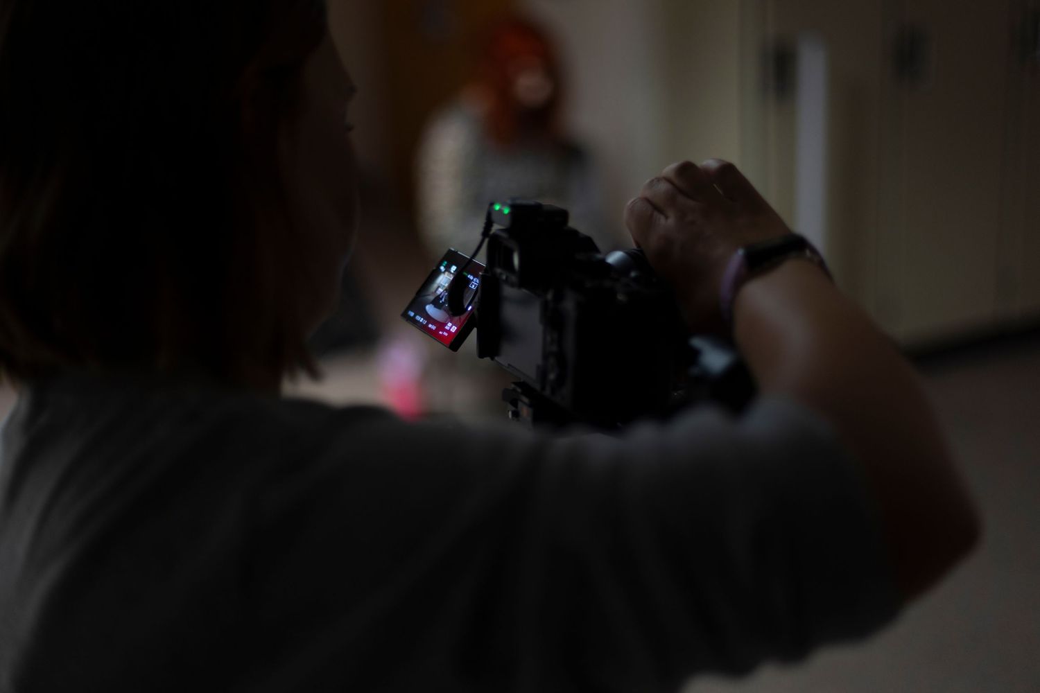 Photographer holds a camera while capturing footage in a dimly lit hallway.