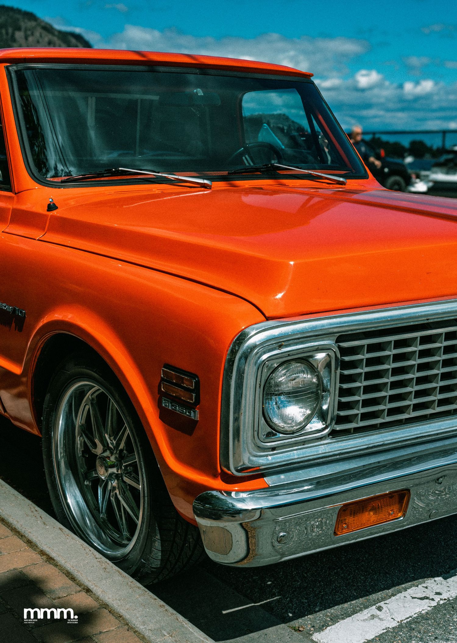 Bright orange classic Chevrolet C10 pickup truck at an outdoor car show.