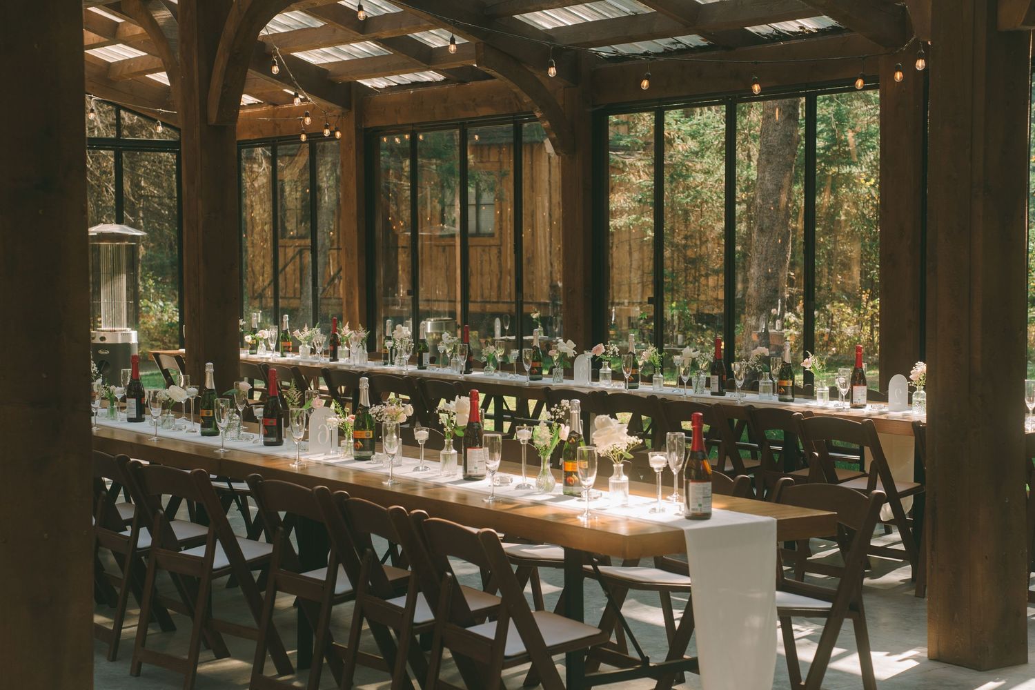 Elegant rustic greenhouse wedding reception with long wooden tables decorated with colorful floral centerpieces.