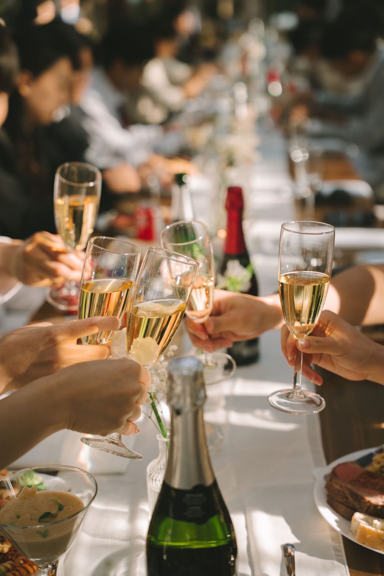 Guests raise champagne glasses in a celebratory toast at a long elegantly set wedding reception table.