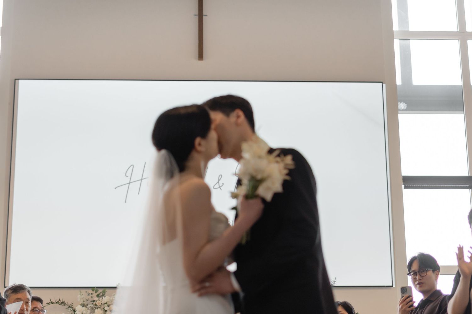 Asian bride and groom share their first kiss at the altar during their wedding ceremony.