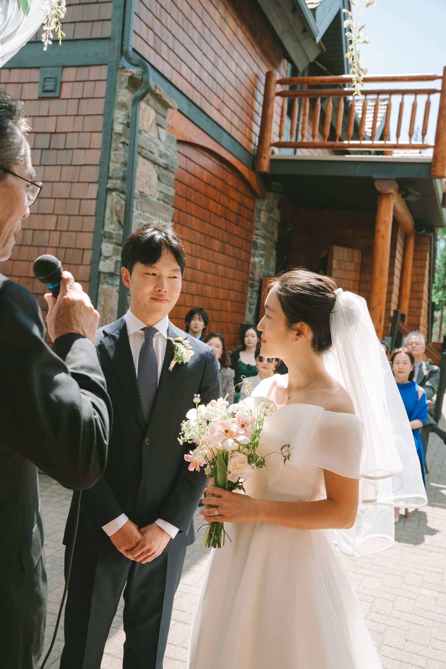 Bride and groom exchange vows outdoors at a mountain lodge wedding ceremony with guests watching.